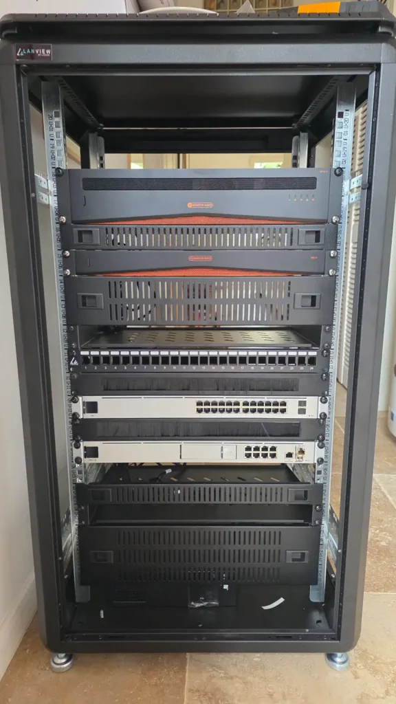 Rack technique installation domotique villa luxe Saint-Tropez — amplificateurs Monitor Audio, switches Ubiquiti UniFi, UDM-SE — intégration réseau et audio haut de gamme par Dotix